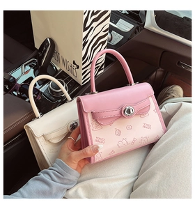 Close-up of contrast color handbag with cartoon prints and metallic twist lock hardware