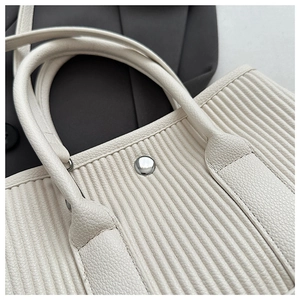 Detail of cream pleated tote bag featuring lychee texture and silver metal hardware
