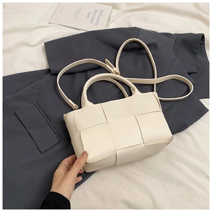 Detail of cream-white woven leather handbag with round handle and skinny shoulder strap