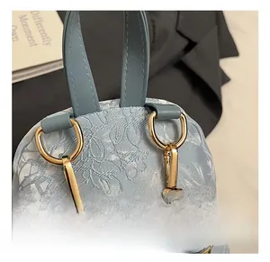 Close-up of light blue jacquard backpack with golden metal hook and leather strap detail