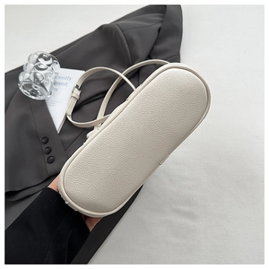 Detail shot of lychee grain leather texture on off-white bucket bag with metal buckle