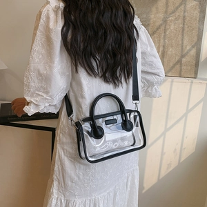 Transparente PVC Jelly Bag mit schwarzem Besatz und breitem Gurt auf weißem Kleid
