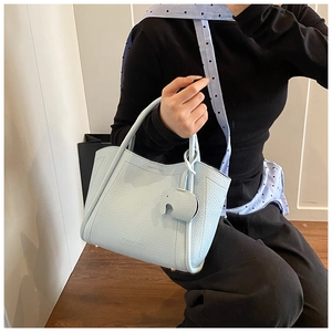 Detailed macro view of light blue lychee pattern leather bucket bag with elephant charm