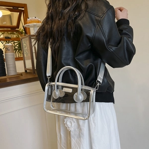 Transparente PVC-Handtasche mit silbernem Rand und breitem Schultergurt getragen am Modell
