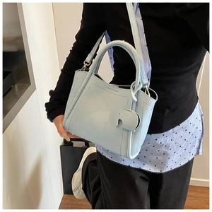 Detail of light blue lychee pattern leather bucket bag with elephant charm and strap