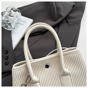 Close-up of pleated cream leather texture and handle on a minimalist bucket bag
