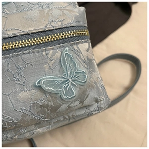 Gros plan détaillé de la broderie papillon bleue et du tissu jacquard du mini sac à dos