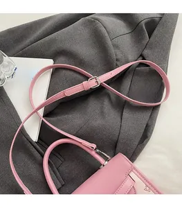 Detail view of pink leather bag featuring an adjustable silver buckle and matching strap