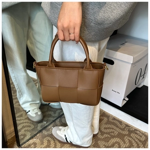 Brown woven leather tote bag shown in a real-life mirror selfie for size reference