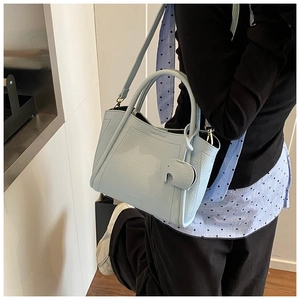 Close-up of light blue pebble grain leather bucket bag with cute elephant charm and strap