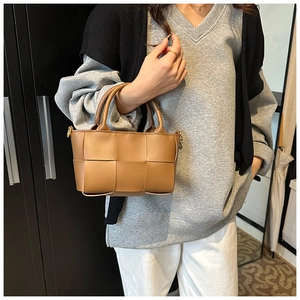 Detailed close-up of brown woven mini tote bag with round handle and gold hardware