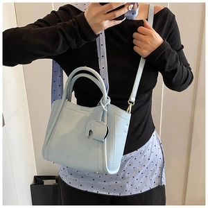 Detail of light blue pebble leather bucket bag with cute elephant charm and STANDOIL logo