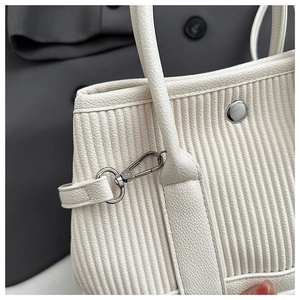Detailed close-up of white pleated handbag showing silver hardware and grain texture