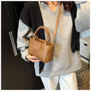 Close-up of brown woven leather texture and crossbody strap on stylish square handbag