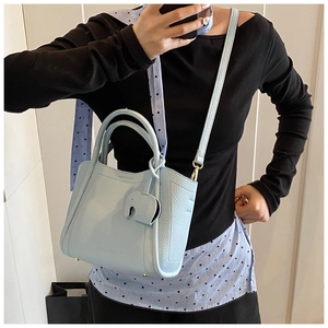 Detail of light blue lychee leather bucket bag with elephant charm and gold hardware