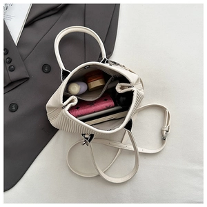 Detail view of the pleated white bucket bag interior with zipper pocket and daily essentials