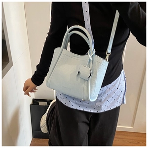 Detail of light blue pebble leather bucket bag featuring a cute elephant charm and strap