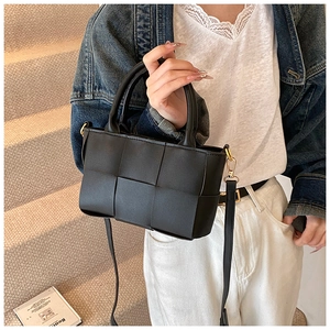 Close-up of black woven leather handbag with detachable gold buckle shoulder strap