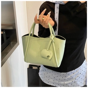 Detail of light green bucket bag with lychee texture leather and cute elephant charm