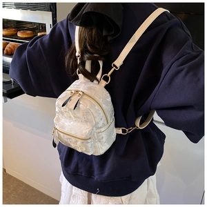 Detail view of mini white backpack with floral embroidery and golden metal zippers
