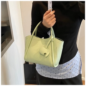 Detail of light green pebble leather bucket bag featuring a cute elephant charm