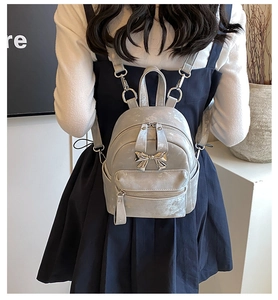 Détail d'un mini sac à dos argenté avec nœud métallique et bretelles sur un modèle