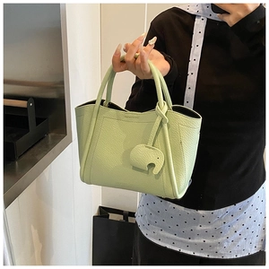 Detail of light green litchi grain leather bucket bag featuring a cute elephant charm