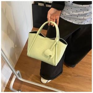 Detail of light green bucket bag with lychee texture and elephant leather charm