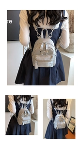 Détail d'un mini sac à dos argenté avec un nœud métallique et un cuir argenté texturé