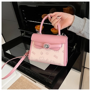Detailed view of pink cartoon embossed handbag with silver metal twist lock and top handle