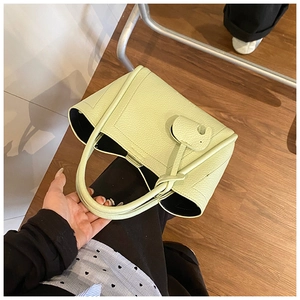 Detail view of light green lychee pattern leather bucket bag with knot tassel decoration