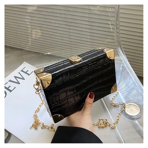 Detail of black faux crocodile leather box bag with gold metal corners and chain