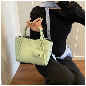 Detail of light green pebble leather handbag featuring a cute elephant charm