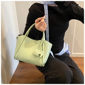 Detail view of mint green bucket bag featuring pebbled leather texture and elephant charm