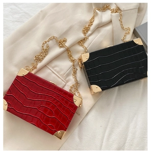 Close-up of crocodile pattern box bags in black and red with gold rivet corners