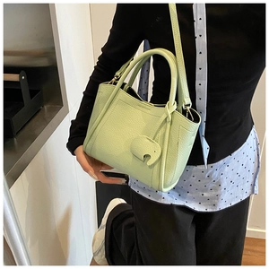 Detail of lime green litchi texture leather handbag with cute elephant charm
