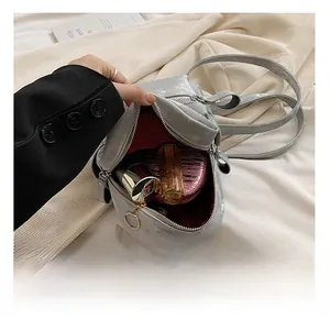 Détail de l'intérieur d'un mini sac à dos gris montrant le rouge à lèvres et le poudrier