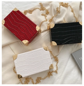 Detail of vintage box bags in burgundy, black, and white with crocodile texture