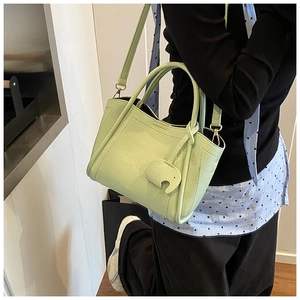 Detail of light green pebbled leather bucket bag featuring a cute elephant charm accessory