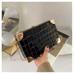 Detail of black crocodile texture clutch bag with gold corners and retro clasp buckle