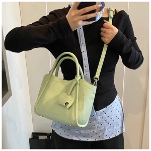 Close-up of mint green bucket bag with lychee grain leather and elephant pendant charm