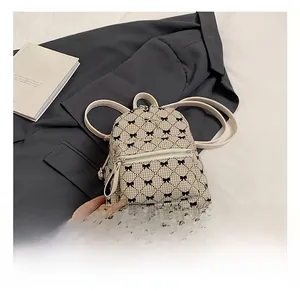 Close-up of beige plaid backpack with black bow patterns on a grey suit background
