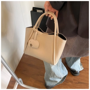 Close-up of beige bucket bag in lychee pattern leather with a cute elephant charm
