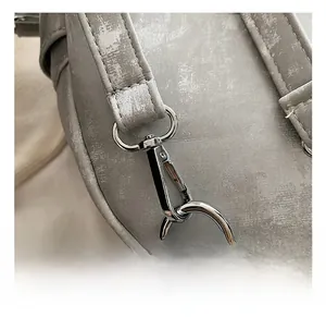 Gros plan sur le crochet métallique argenté et les coutures renforcées d'un sac gris
