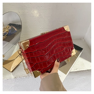 Detail of red crocodile texture box bag with gold metal corners and chain strap