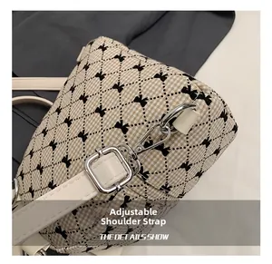 Detail of adjustable white leather shoulder strap with silver buckle on bow pattern bag