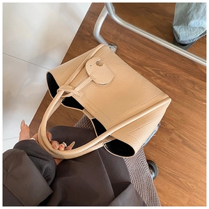 Detail of apricot pebbled leather bucket bag featuring a unique C-shaped buckle and handles