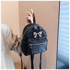 Détail d'un mini sac à dos noir avec nœud métallique argenté et texture vintage