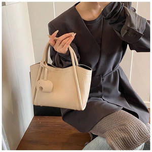 Detail of cream pebbled leather bucket bag with round handles and elephant charm
