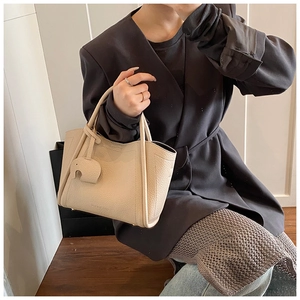 Detail of cream pebbled leather tote bag with elephant charm and stitched side accents